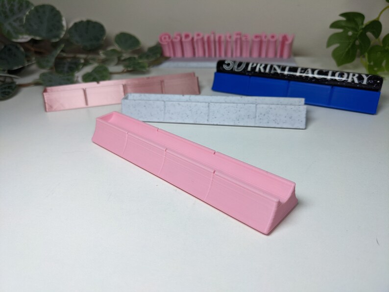 May include: A pink plastic organizer with four compartments. The organizer is designed to hold small items, such as pens, pencils, or other office supplies.