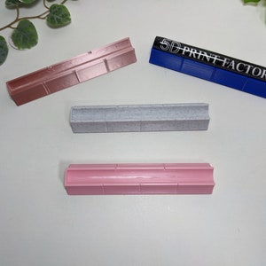 May include: Three different colored plastic molds for making resin crafts. The molds are all rectangular and have a groove down the center. The blue mold has the text "5D PRINT FACTORY" printed on it.