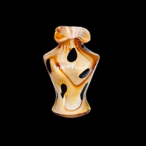 May include: A brown and white glass vase with black spots. The vase has a wide mouth and a narrow base.