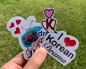 May include: A collection of Korean drama themed stickers. The stickers feature a retro television with the South Korean flag, a hand making the Korean heart sign, a heart with the text "I love Korean Drama", and a heart with the text "K-Drama".