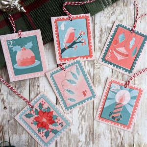 Pu&ograve; includere: Sei etichette regalo di Natale con un design in stile vintage. Ogni etichetta presenta un'immagine festiva diversa, tra cui un pettirosso, un budino di Natale, una candela, una stella di Natale e luci di Natale. Le etichette sono stampate su carta testurizzata con sfondo rosa e bordo turchese.
