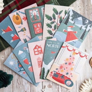 May include: A set of 10 Christmas cards featuring various winter scenes, including a snowman, a Christmas tree, and a Santa Claus. The cards are all decorated with festive colors and patterns.