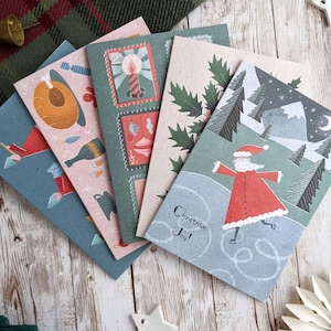 May include: Set of four Christmas cards featuring illustrations of a candle, holly, a snowman, and Santa Claus. The cards are printed on a textured paper stock and have a vintage aesthetic. The text on the cards reads "Christmas Joy!"