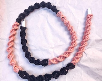 May include: A black and pink braided charging cable with two white USB connectors.