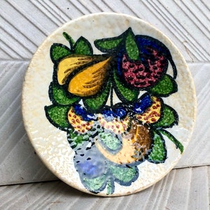 Peut inclure: Une assiette en céramique blanche avec un motif floral. Les fleurs sont jaunes, rouges et bleues avec des feuilles vertes. L'assiette a une surface texturée.