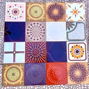 May include: A collection of sixteen square ceramic tiles arranged in a four-by-four grid. Each tile features a unique design, including floral patterns, geometric shapes, sunburst motifs, and solid colors in shades of blue, orange, yellow, and brown.