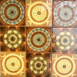 Peut inclure: Neuf carreaux de céramique carrés avec un motif répétitif de cercles concentriques bruns, jaunes, verts et bleus. Les carreaux sont disposés en grille de 3x3.