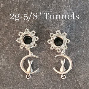 May include: A pair of silver 2g-5/8" tunnels with a dangling crescent moon charm featuring a cat silhouette.