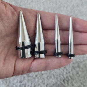 May include: Four silver metal spike plugs of different sizes with black rubber o-rings.