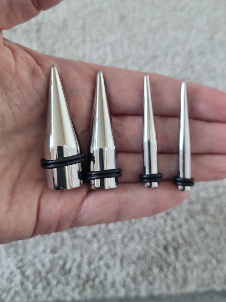 May include: Four silver metal spike plugs of different sizes with black rubber o-rings.