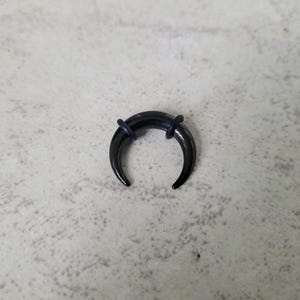 May include: Black crescent moon shaped body jewellery with black o-rings.