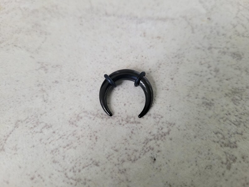 May include: Black crescent moon shaped body jewellery with black o-rings.