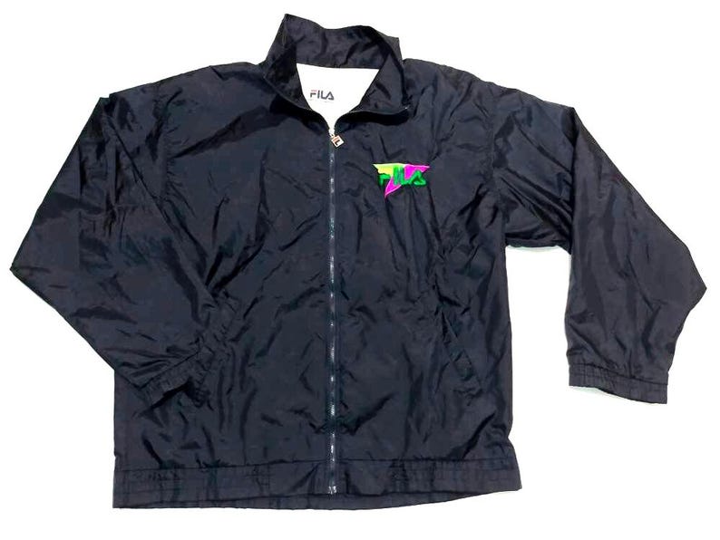 May include: Black FILA jacket with a full-length zipper and a small logo on the chest. The logo is a stylized design in neon green, pink, and yellow. The jacket has a stand-up collar and elastic cuffs.