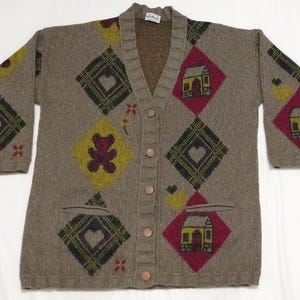 May include: A brown cardigan sweater with a V-neck and button closure. The sweater features a diamond pattern with hearts, houses, and teddy bears in red, yellow, and green. The sweater has two pockets.