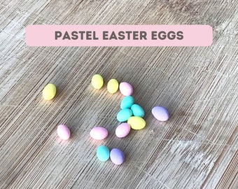 May include: Pastel Easter eggs in yellow, blue, pink, and purple colors scattered on a wooden surface.