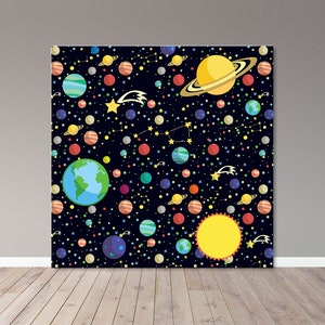 Puede incluir: Un colorido telón de fondo con temática espacial que presenta planetas, estrellas y cometas sobre un fondo azul oscuro. Los planetas se representan en varios colores, incluyendo azul, rojo y amarillo, con Saturno en un lugar destacado. El telón de fondo está sobre una pared gris y un suelo de madera.