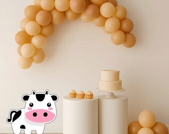 May include: A party scene featuring a balloon arch in beige and brown tones. A two-tiered cake and cupcakes are displayed on white pedestals. A cartoon cow graphic is in the lower left. Balloons are clustered on the right.
