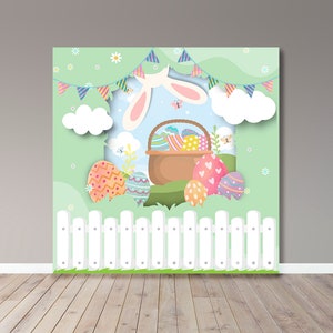 May include: An Easter-themed backdrop featuring a white picket fence, colorful Easter eggs, and a basket filled with decorated eggs. A bunny's ears peek from behind a banner of pastel flags. The background is a light green with clouds and flowers.