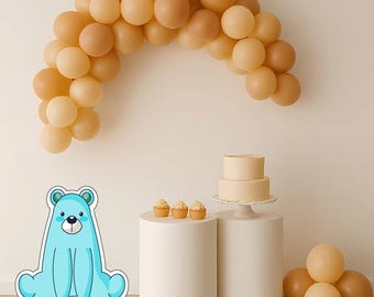 May include: A party scene featuring a light blue bear cutout, a balloon arch, a two-tiered cake, cupcakes, and white pedestals. The balloons are in beige and brown tones, creating a warm atmosphere. The cake and cupcakes are beige.