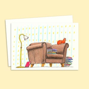 Cartão de felicitações "Gato Estudioso" - Ilustração desenhada à mão de um gato aconchegante em uma poltrona cercado por livros - Em branco por dentro