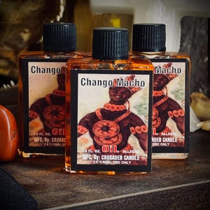 May include: Three small bottles of oil with black caps. Each bottle has a label with the words "Chango Macho" and an illustration of a figure. The labels also include the text "1/2 FL OZ OIL" and "EXTERNAL USE ONLY".