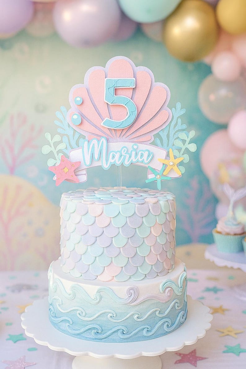 May include: A two-tiered cake with a mermaid theme. The cake is decorated with pastel colors and a scale pattern. A topper features the number 5 and the name "Maria". The bottom tier has a wave design.