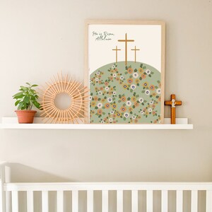 K&ouml;nnte beinhalten: Ein gerahmter Druck mit gr&uuml;nem Hintergrund und einem Blumenmuster. Der Druck zeigt drei Holzkreuze und den Text "He is Risen, Alleluia".
