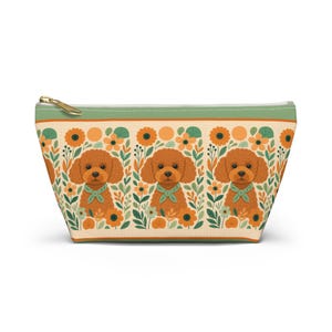 May include: A beige zippered pouch featuring a repeating pattern of cartoon poodles, sunflowers, and foliage. The poodles are brown with green bowties. The top border is green with a gold zipper.