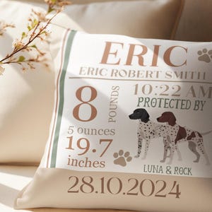 May include: A white pillow with brown text and a graphic of two dogs. The text reads "ERIC* ERIC ROBERT SMITH 8 POUNDS 5 ounces 19.7 inches 10:22 AM PROTECTED BY LUNA & ROCK 28.10.2024".