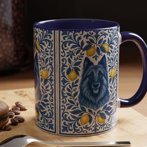 May include: A ceramic mug with a dark blue interior and handle. The exterior features a blue and cream floral pattern with yellow lemons and a portrait of a dog. The mug is sitting on a wooden surface.