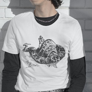May include: A white t-shirt with a black and white illustration of a snake wrapped around a dog's head.