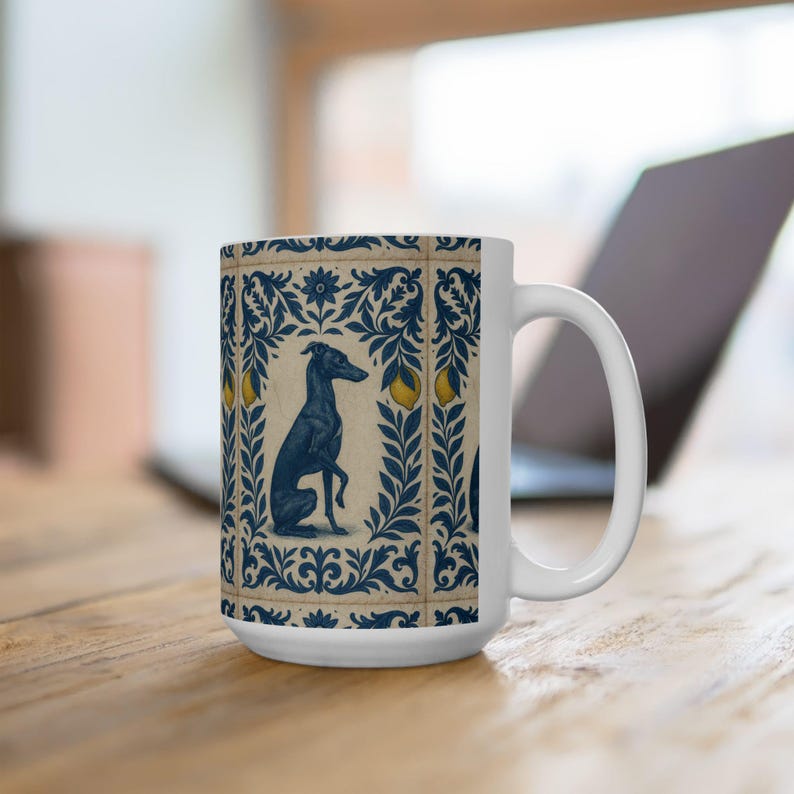 May include: White ceramic mug featuring a blue and cream design with a greyhound illustration. The design includes floral elements and yellow fruit accents. The mug has a curved handle and is suitable for hot or cold beverages.