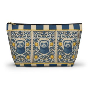 Può includere: Un astuccio con cerniera con un motivo ripetuto di furetti blu e limoni gialli su sfondo crema. Il design è incorniciato da elementi floreali blu e crema ornati. La parte superiore presenta strisce blu e crema.