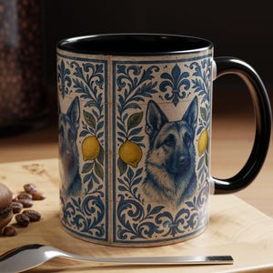 May include: A ceramic mug with a black handle and interior. The mug features a German Shepherd portrait, lemons, and blue floral patterns. The design is set against a cream background.