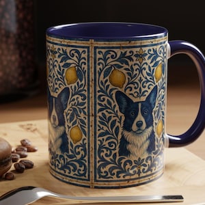 May include: A ceramic mug with a blue interior and handle. The exterior features a repeating pattern of a blue and white corgi dog, yellow lemons, and blue floral designs. The mug sits on a wooden surface.