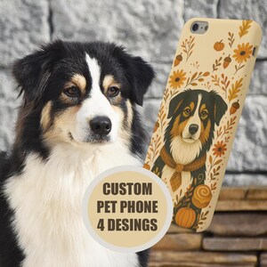 May include: An Australian Shepherd dog with black, white, and tan fur stands beside a phone case. The case features a dog illustration, pumpkins, and autumn leaves on a beige background. The image includes the text "CUSTOM PET PHONE 4 DESIGNS."