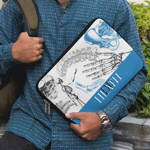 May include: A black laptop sleeve featuring anatomical illustrations of the human skeletal system in blue and gray. The sleeve has a blue stripe with the word "HEALTH" printed vertically in white.