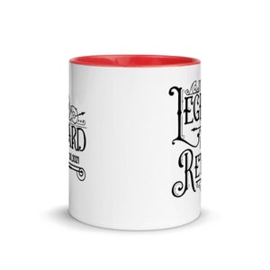 Peut inclure: Une tasse en c&eacute;ramique blanche avec un bord rouge. La tasse a un texte noir qui dit "The Legend is Retired" et un petit motif sur le c&ocirc;t&eacute; gauche qui dit "Retired 01.2021".