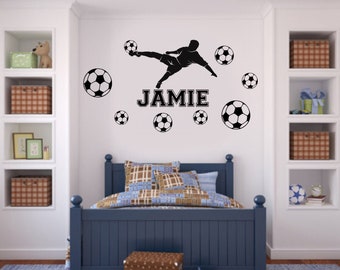 May include: A black silhouette of a soccer player kicking a ball with the name Jamie in black letters. The wall decal is surrounded by black and white soccer balls.