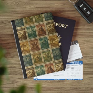 Könnte beinhalten: Ein Reisepasshülle mit einem Vintage-Stempeldesign mit Burgen, Fabelwesen und Landschaften. Sie liegt neben einem Reisepass, einer Bordkarte und einem Autoschlüssel auf einer Holzoberfläche. Die Briefmarken haben verschiedene Werte.