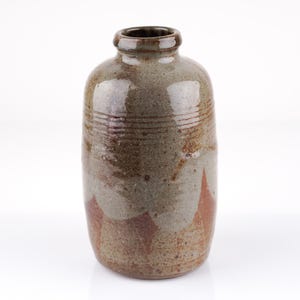 Könnte beinhalten: Eine handgefertigte Keramikvase mit rundem Körper und schmalem Hals. Die Vase hat eine gesprenkelte, erdige Farbpalette aus Braun, Grau und Rotbraun. Horizontale Linien umkreisen den oberen Teil der Vase.
