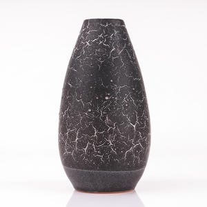 May include: A black ceramic vase with a crackled glaze finish. The vase has a rounded, teardrop shape.