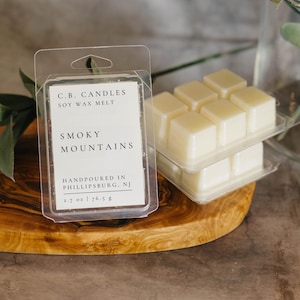 May include: A clear plastic package containing six white soy wax melts labeled "C.B. CANDLES SOY WAX MELT SMOKY MOUNTAINS HANDPOURED IN PHILLIPSBURG, NJ 2.7 oz | 76.5 g"