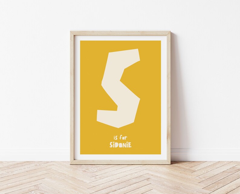 May include: A yellow poster with a white letter S and the text "S is for Sidonie".