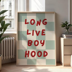Puede incluir: Impresión artística enmarcada con las palabras "LONG LIVE BOY HOOD" en letras rojas y en negrita. El fondo es un patrón de cuadros de cuadrados verde claro y crema. La obra de arte se exhibe en una habitación con una ventana y una mesita.