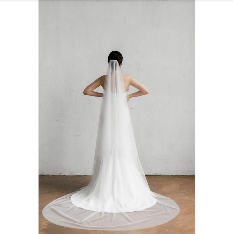 May include: A white bridal veil with a long, flowing design. The veil is made of soft tulle and has a delicate, romantic look.