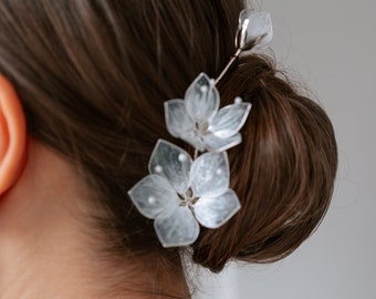 May include: A delicate hair accessory featuring translucent, flower-shaped embellishments. The floral accents are attached to a silver-toned wire, creating a graceful and elegant design. This hairpiece is ideal for weddings or special occasions.