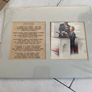 May include: A framed print with two sections. The left side features a poem titled "Father." The right side shows a black and white illustration of a man and a boy in a church setting. The frame is a light blue color.