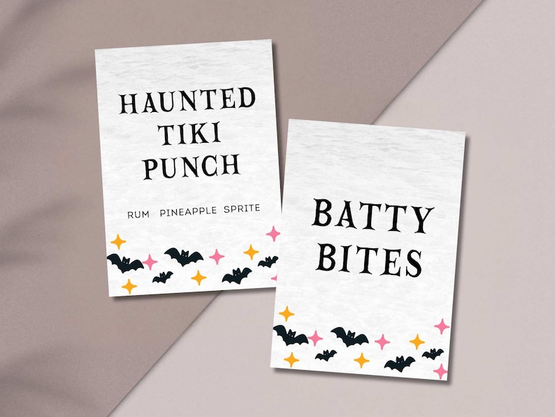 May include: Two white rectangular signs with black text and Halloween-themed graphics. One sign reads "HAUNTED TIKI PUNCH" with "RUM PINEAPPLE SPRITE" below. The other says "BATTY BITES". Both have bats and stars.
