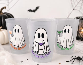 Pode incluir: Três copos de plástico fosco com ilustrações de fantasmas segurando coquetéis. Cada fantasma tem um coquetel diferente e o texto "Here for the boos!" em laranja, roxo e verde. Tema de festa de Halloween.